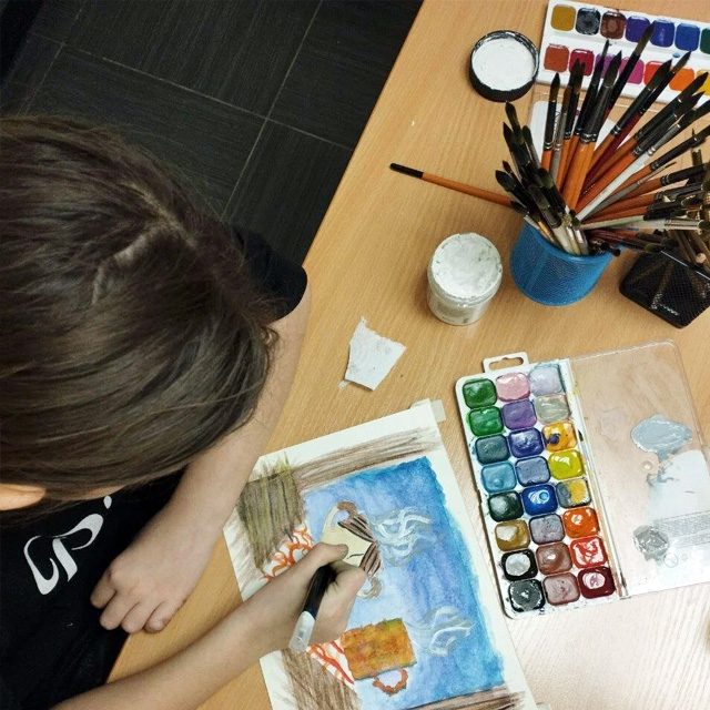 Ученик рисует акварелью за столом